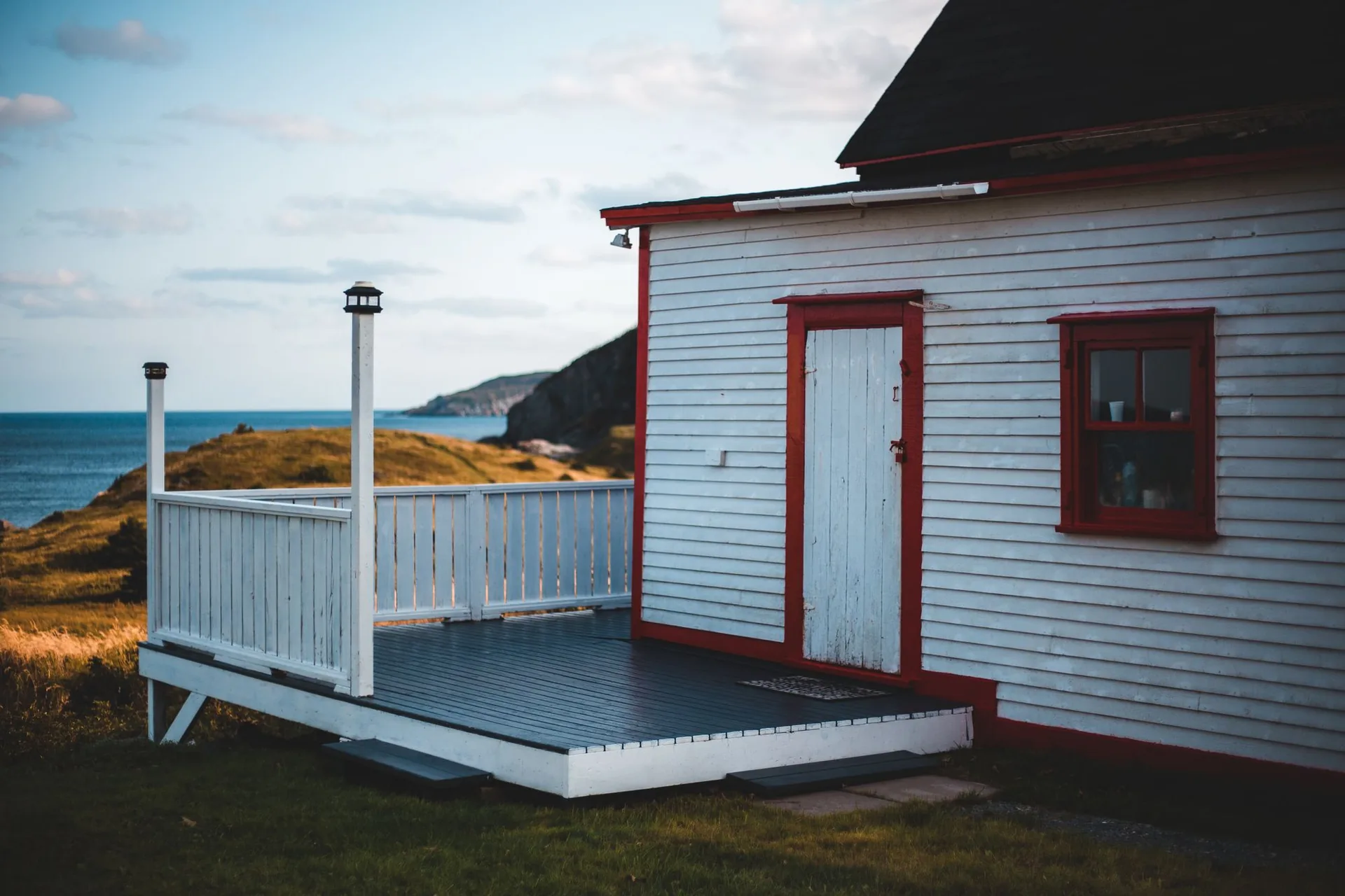 Freshly painted deck beside a white house with red trim