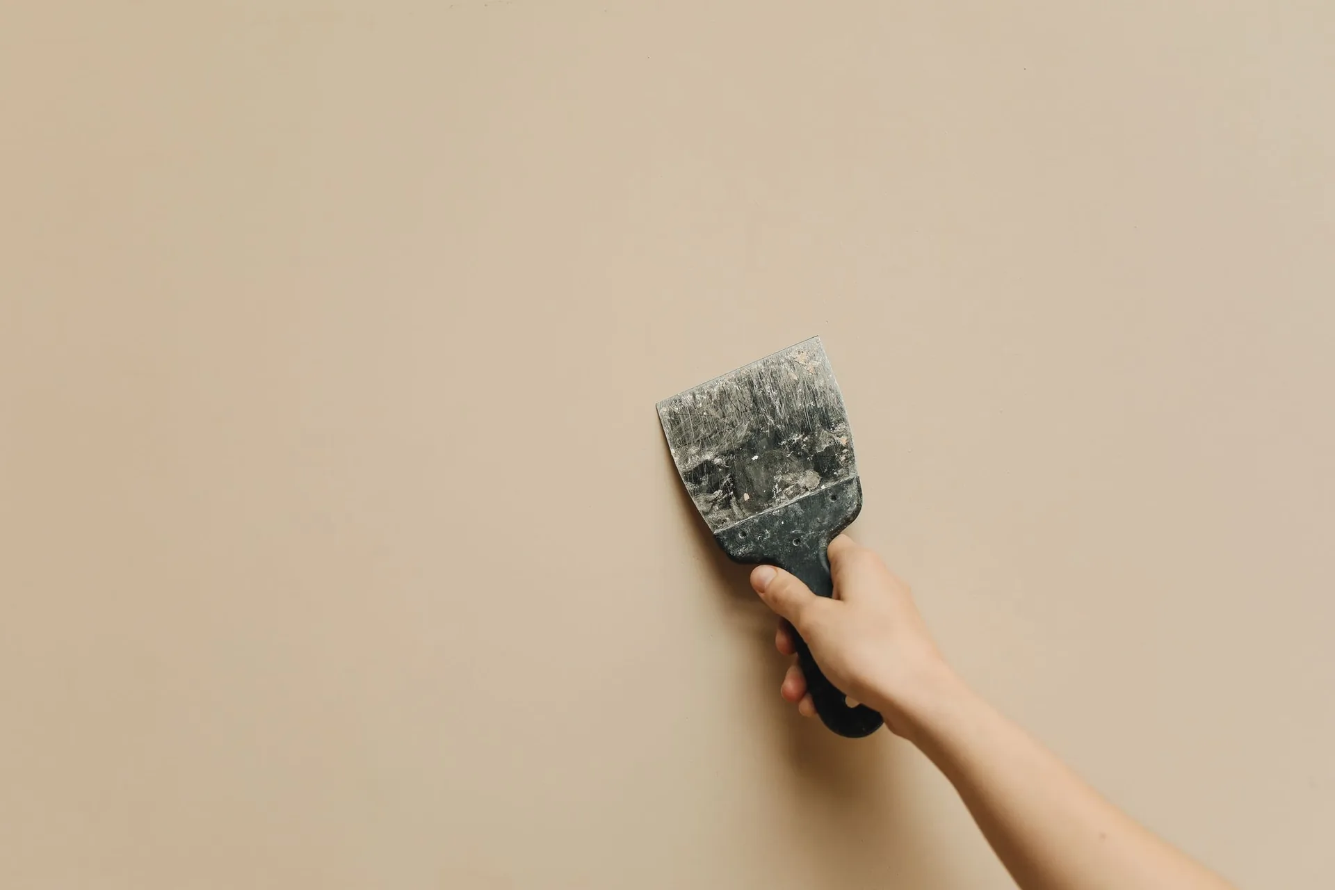Hand applying joint compound to a wall with a putty knife