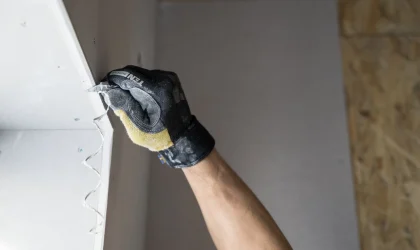 Gloved hand smoothing a drywall panel
