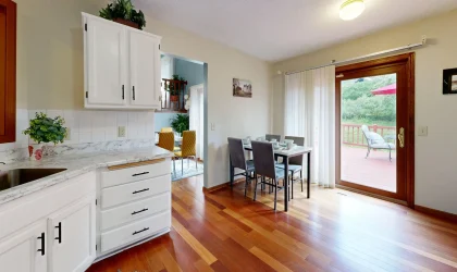 Bright kitchen with white cabinets opening to a dining area